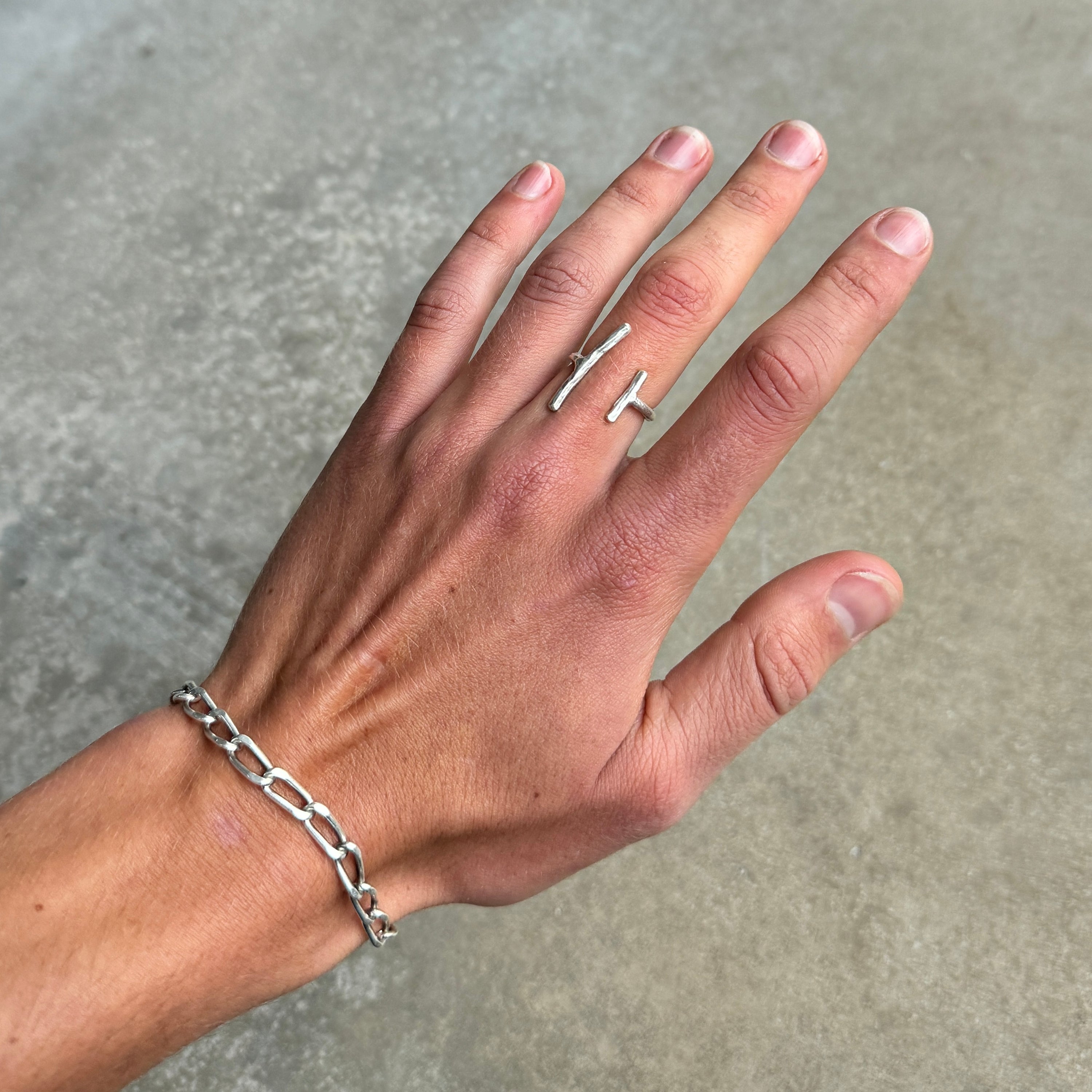 photo of a hand wearing a silver ring with a minimalist 2 lines design