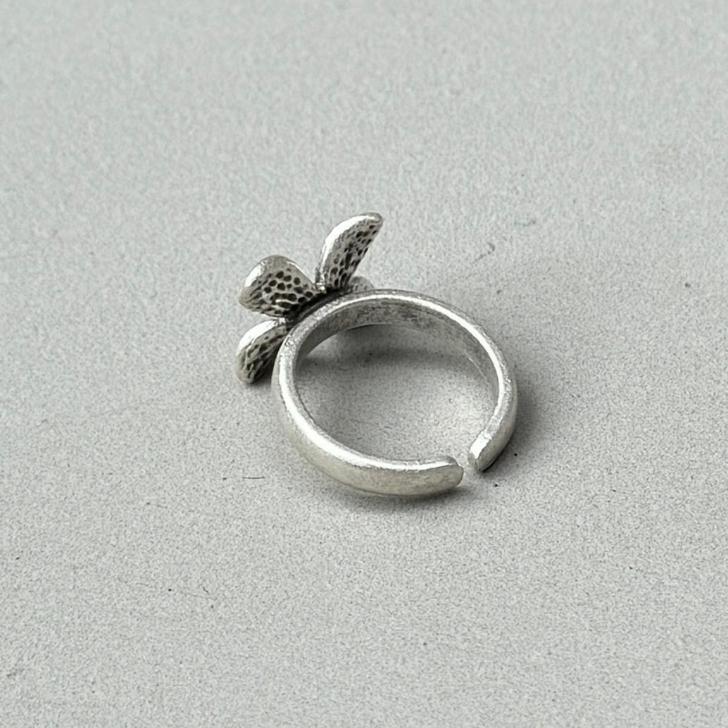 photo of the back of a silver ring with a flower design and an antique style silver finish