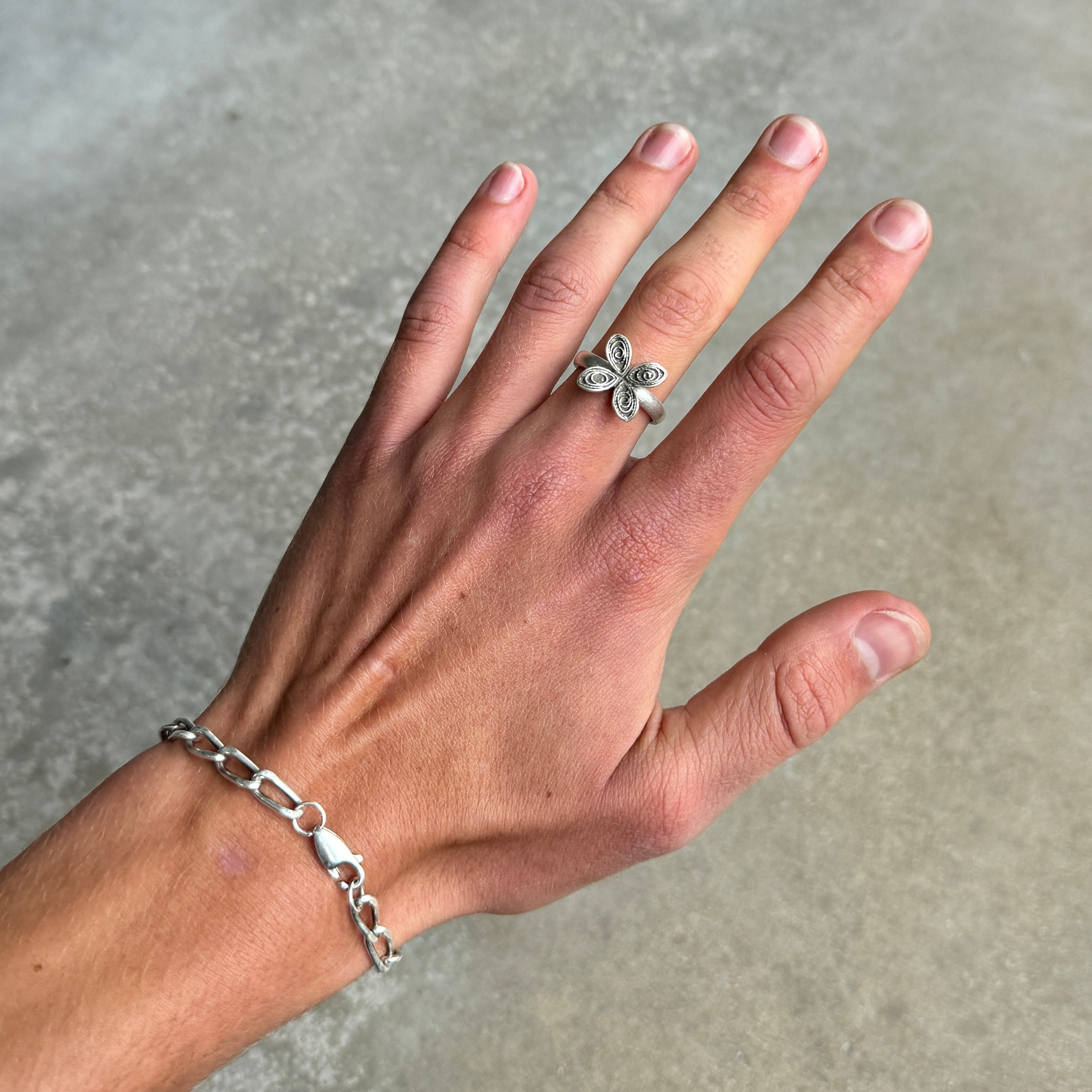 photo of a hand wearing a silver ring with a flower design and an antique style silver finish