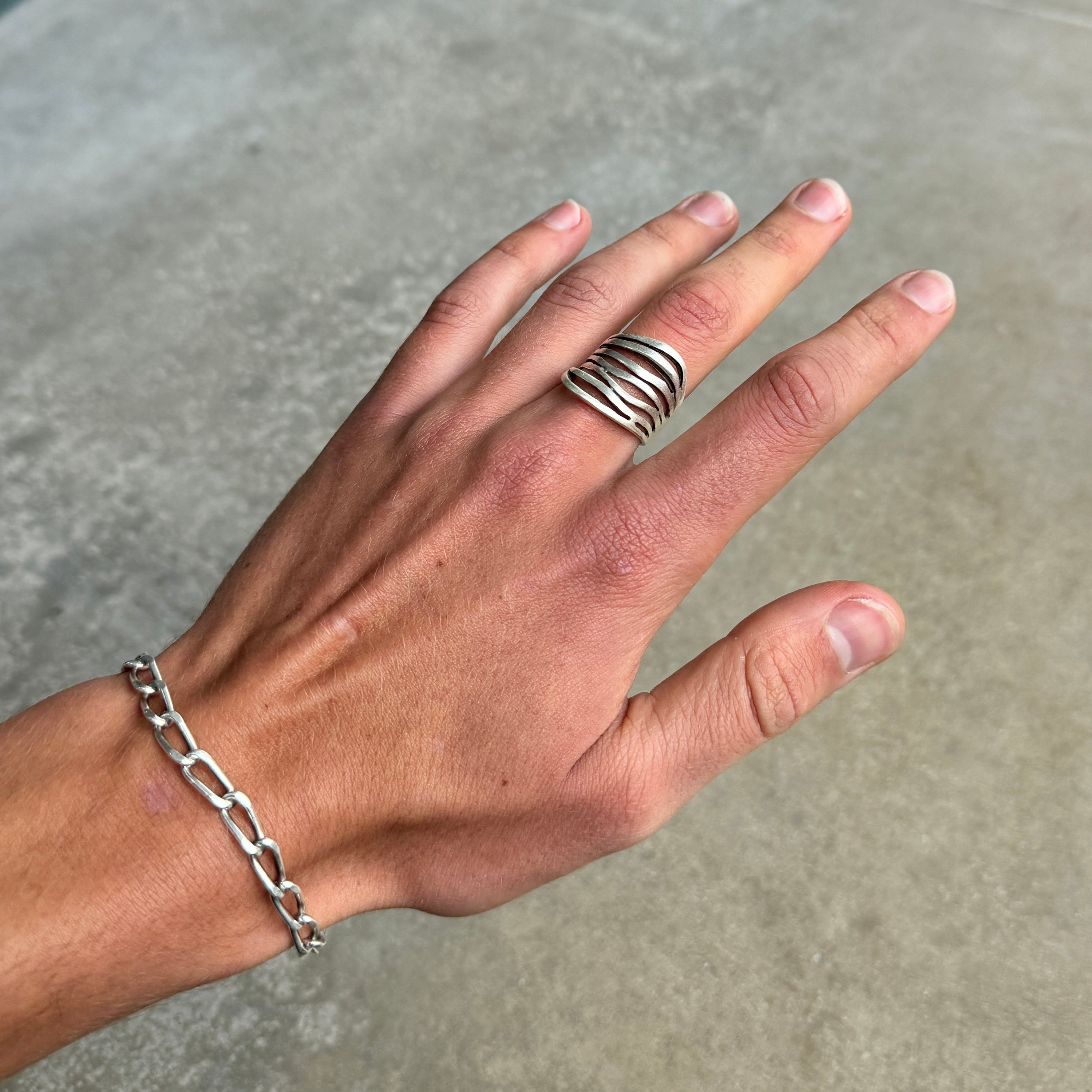 photo of a silver ring with abstract lines and an aged silver finish on a hand