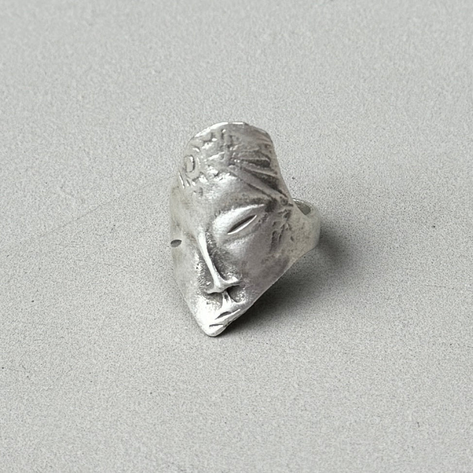 photo of a silver ring with a face design on it and a vintage antique finish to the silver