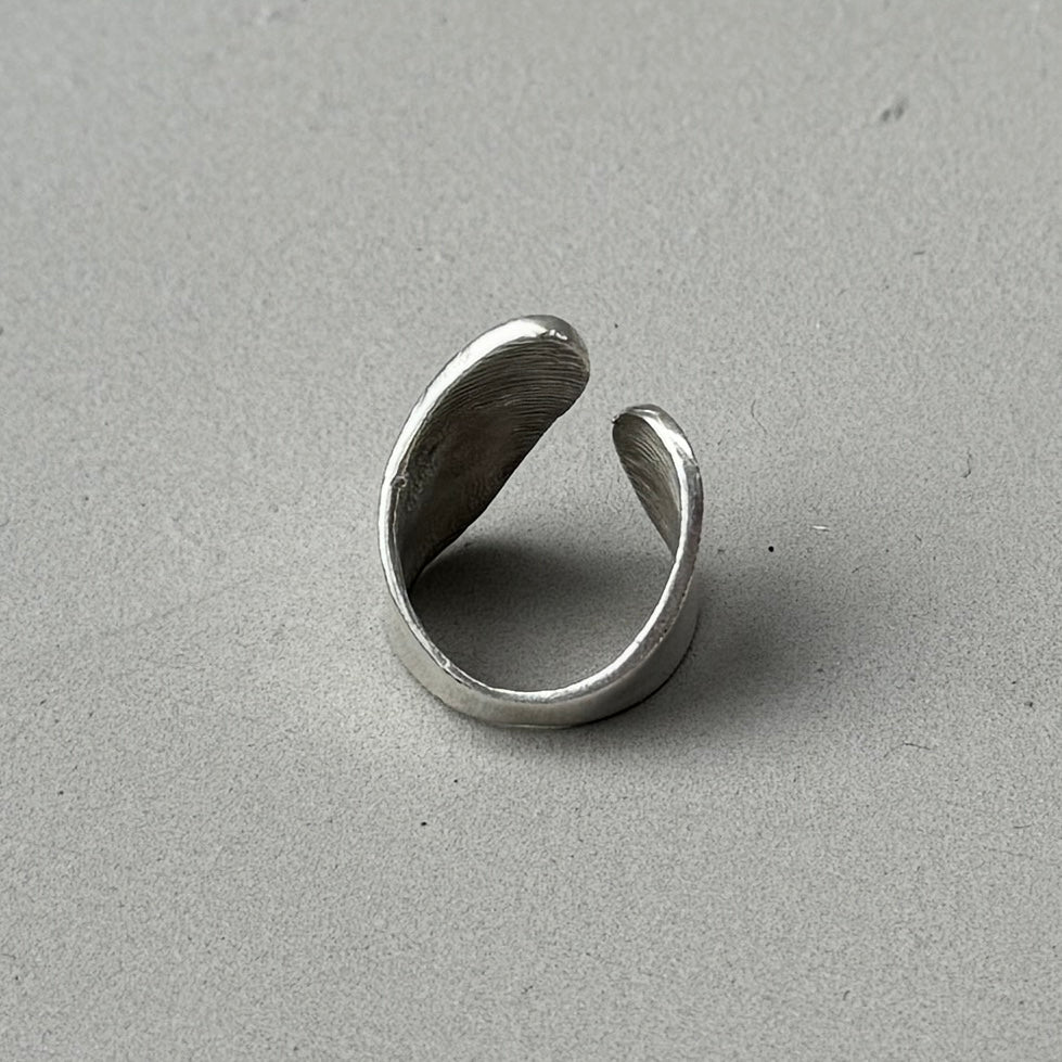 photo of the back of a silver ring with an abstract asymmetric design