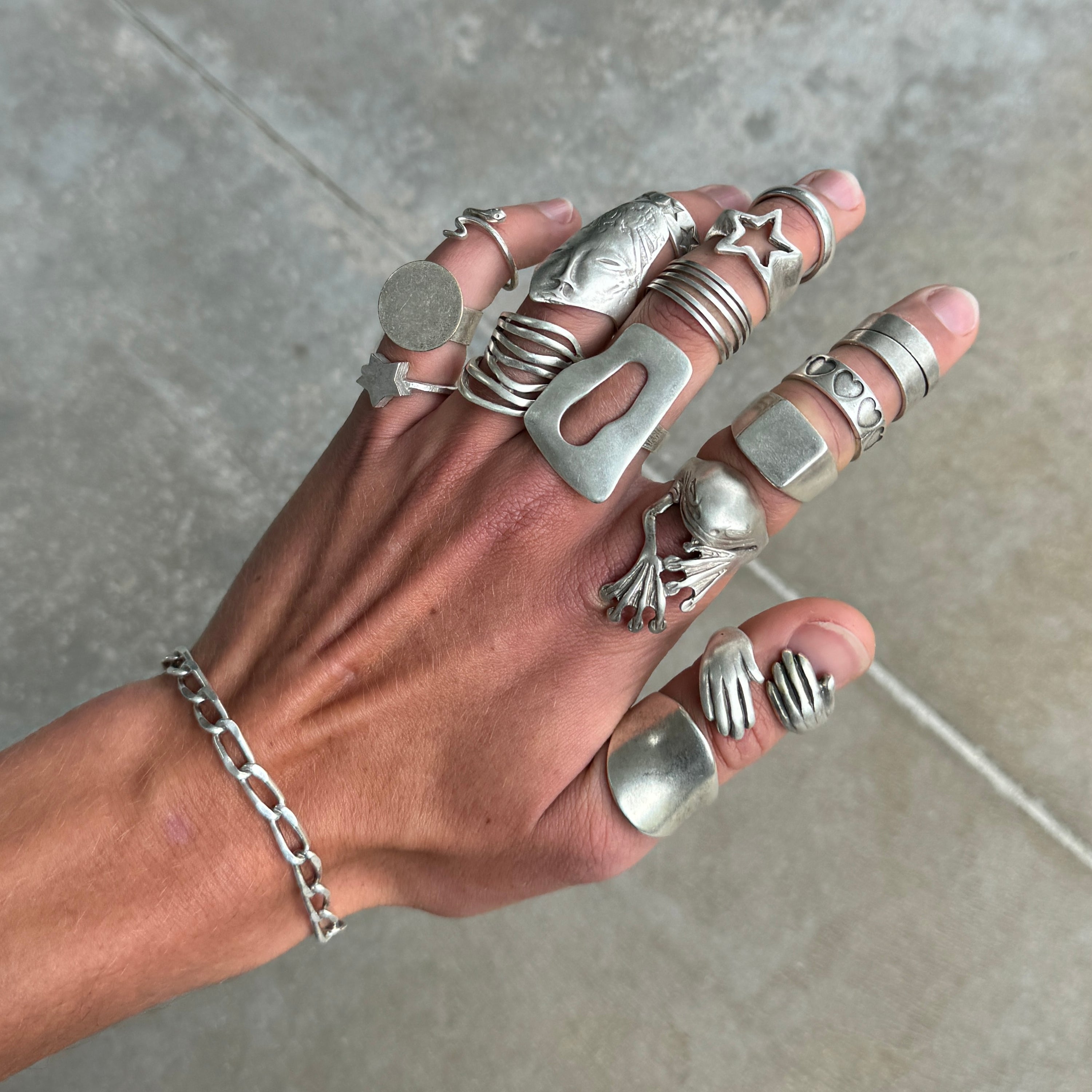 photo of a hand wearing 20 silver rings