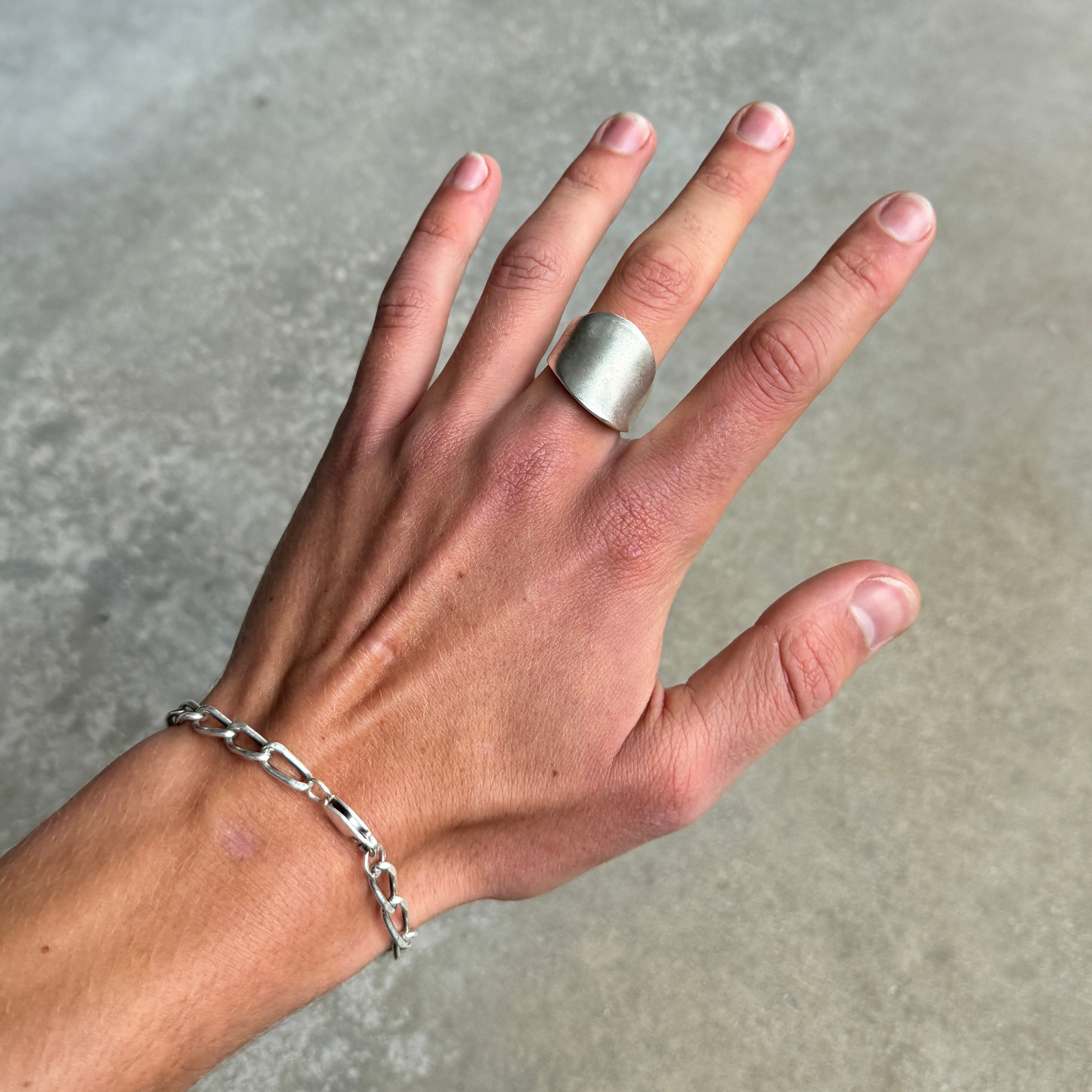 a photo of a hand wearing a silver ring with an oversized asymmetric abstract style and vintage silver finish