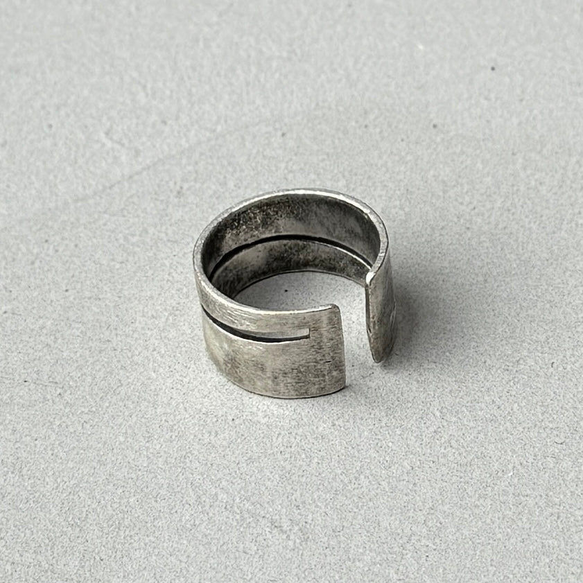 photo of the back of a vintage style silver ring with a cutout diagonal line design