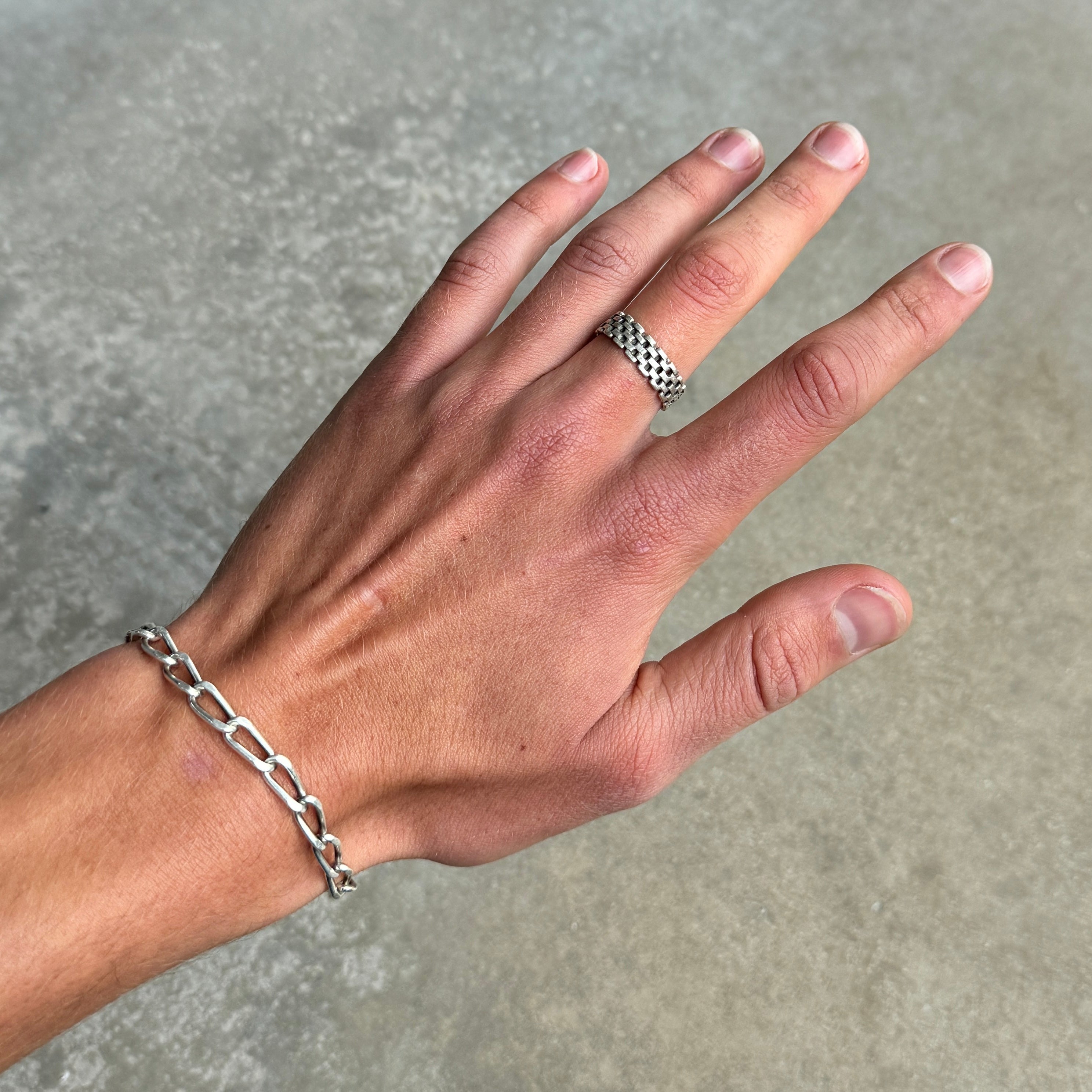 photo of a hand wearing a silver ring with a chain link design 