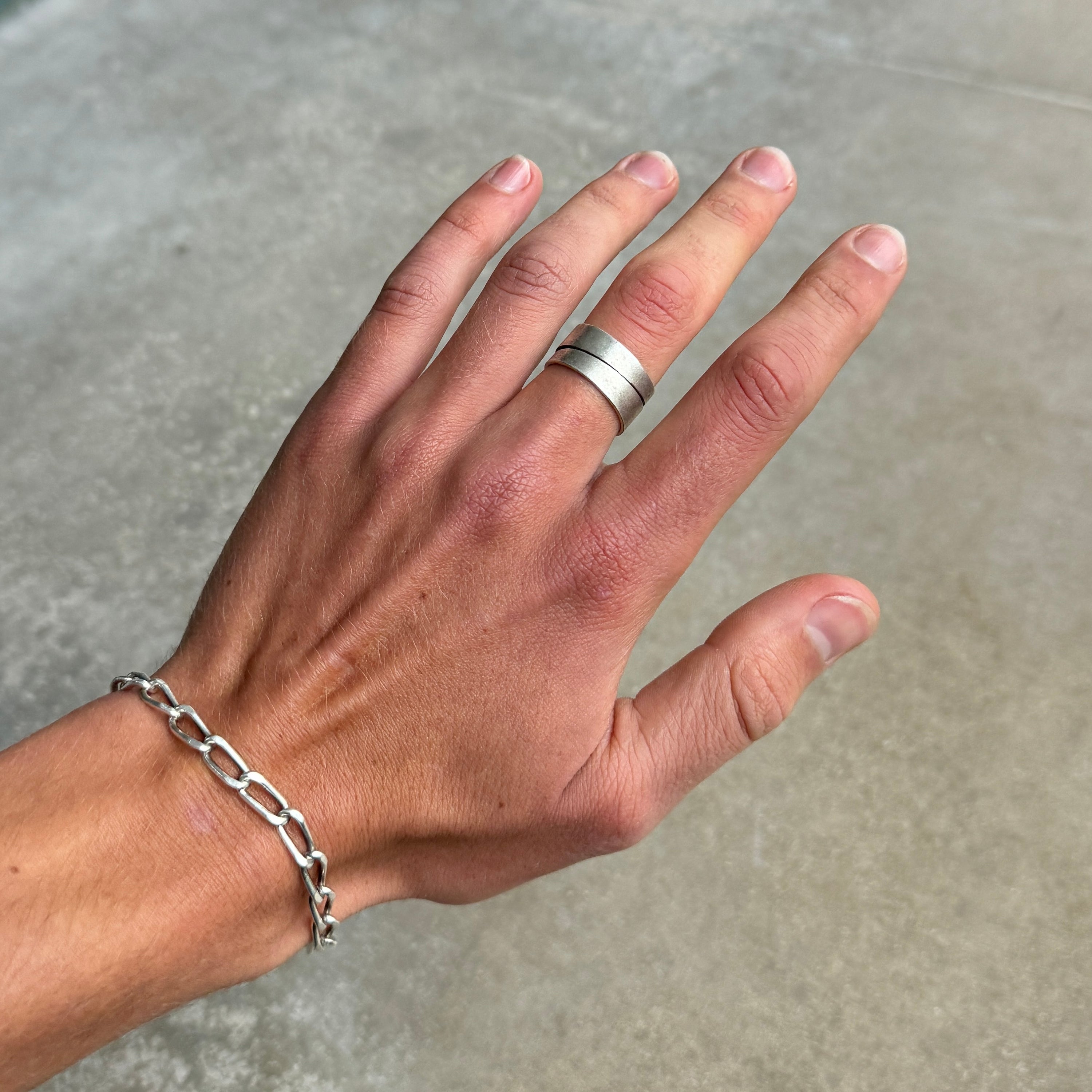 photo of a hand wearing a vintage style silver ring with a cutout diagonal line design