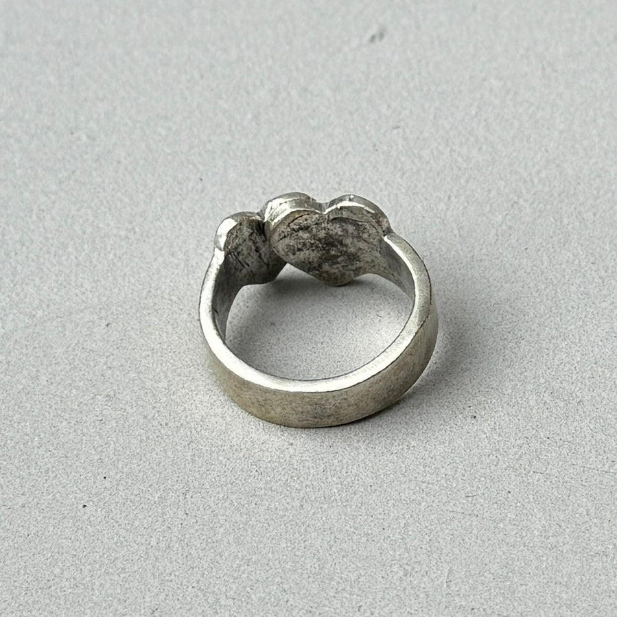 photo of the back of a vintage looking silver ring with a crossed double heart design