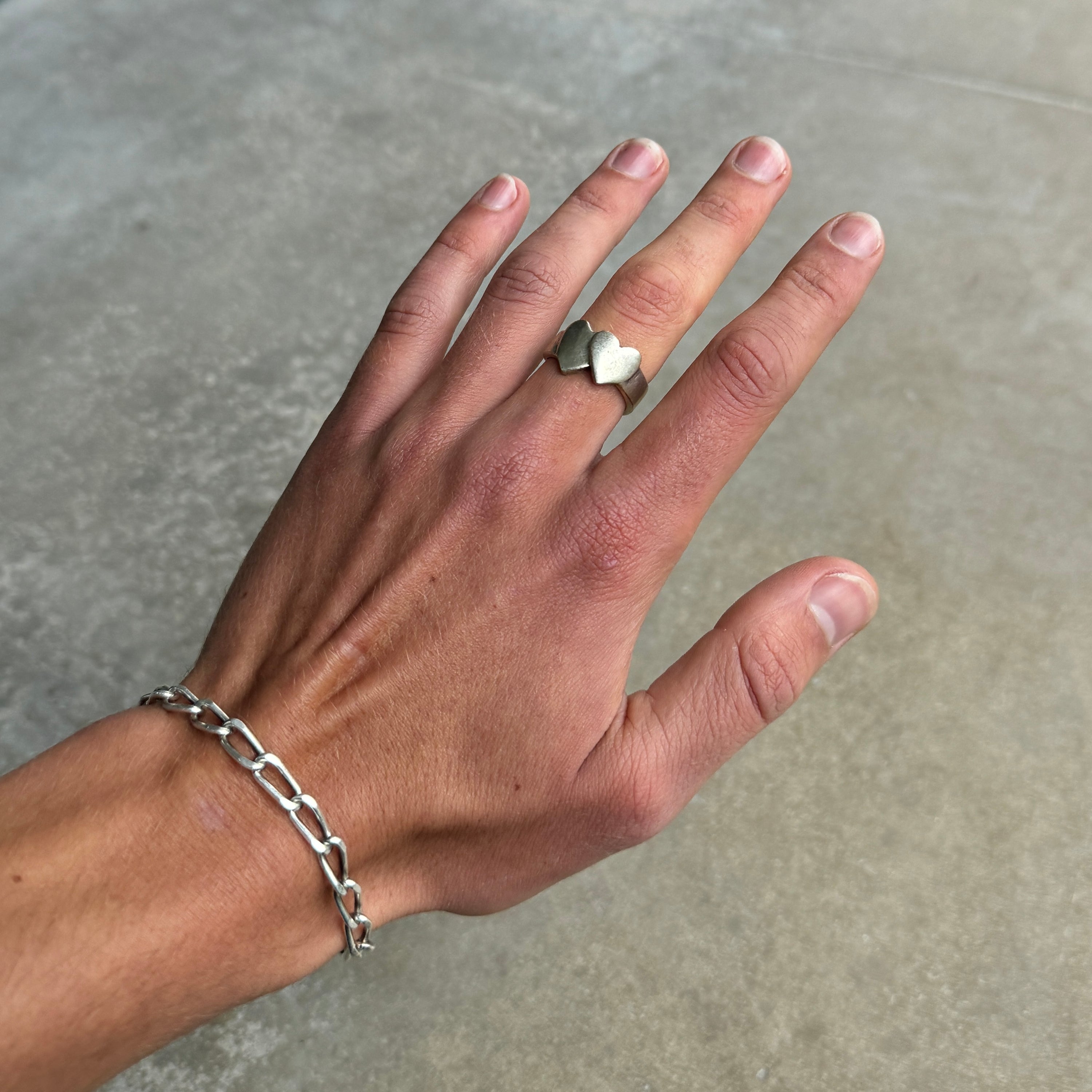 photo of a hand wearing a double heart shaped silver ring