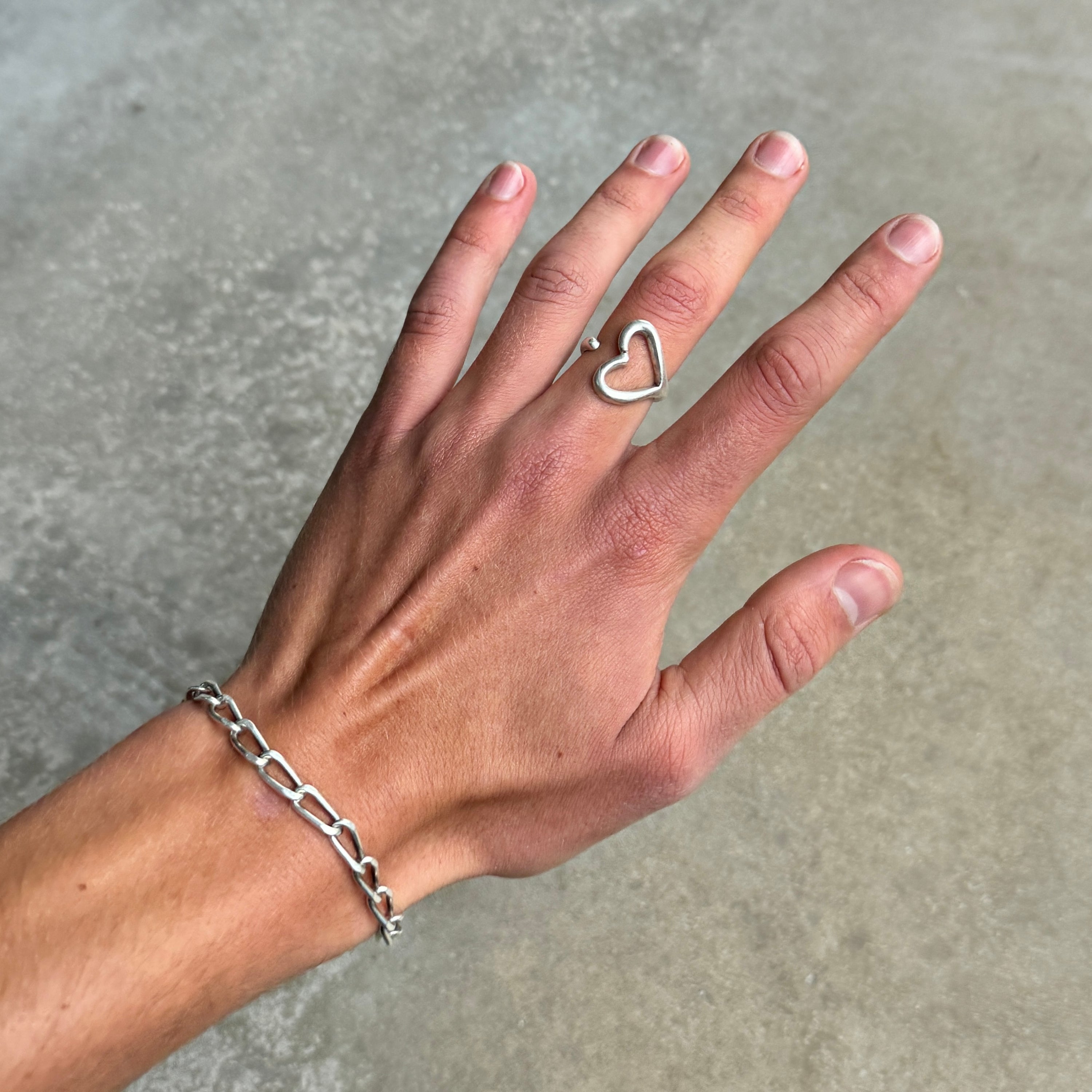 photo of a hand wearing an open heart shaped silver ring