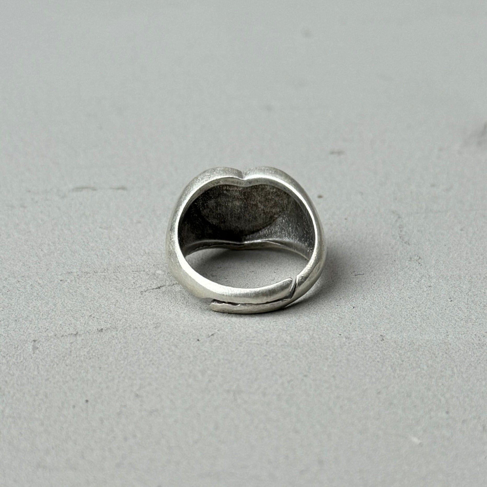 the back of a heart shaped silver ring, with a vintage silver look and adjustable back closure