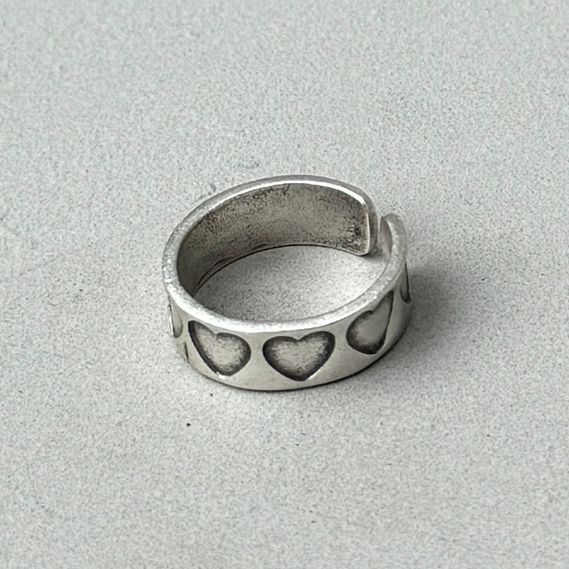 a photo of a silver ring with a stamped hearts design and vintage silver finish