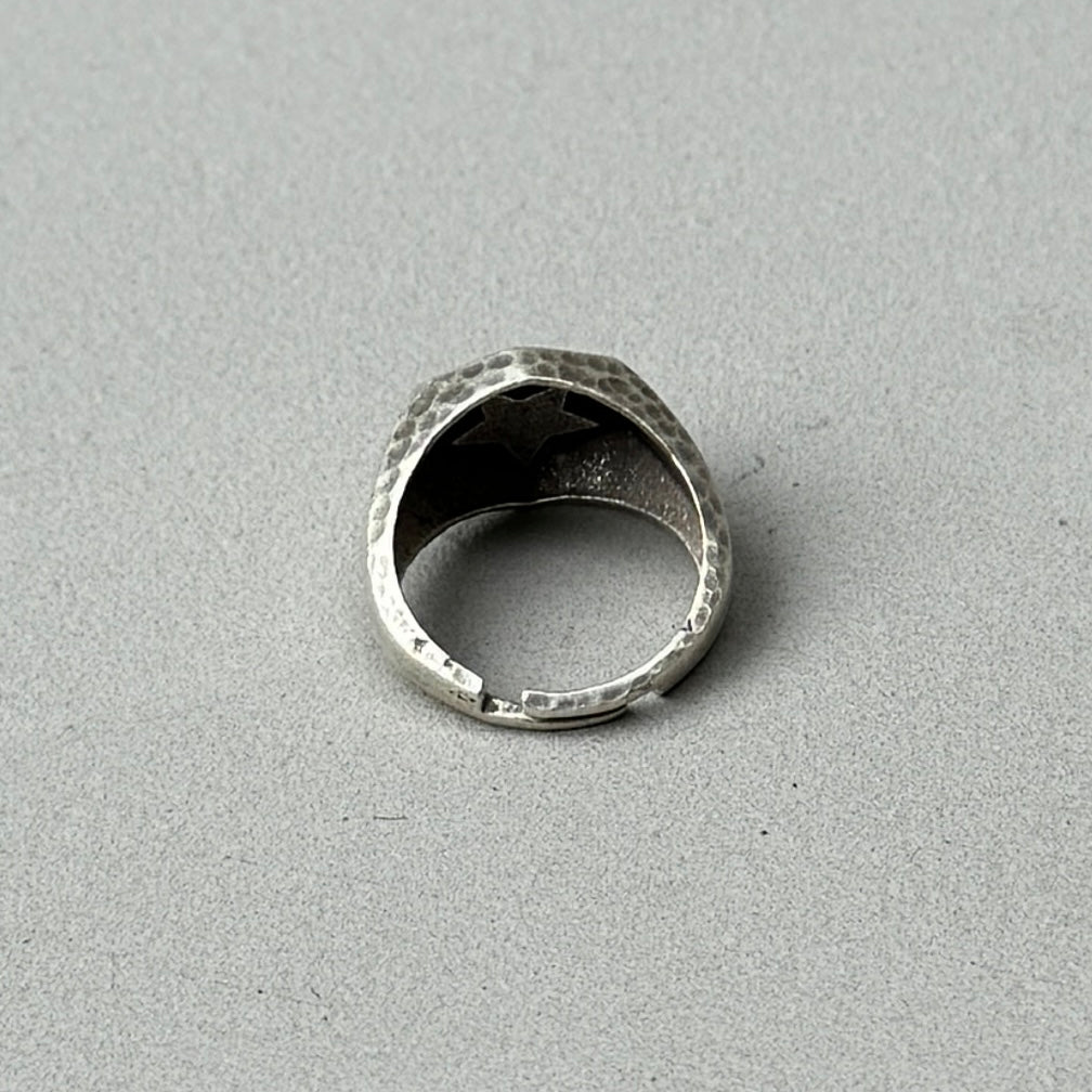 photo of the back of a silver signet ring with a star design engraved on the front