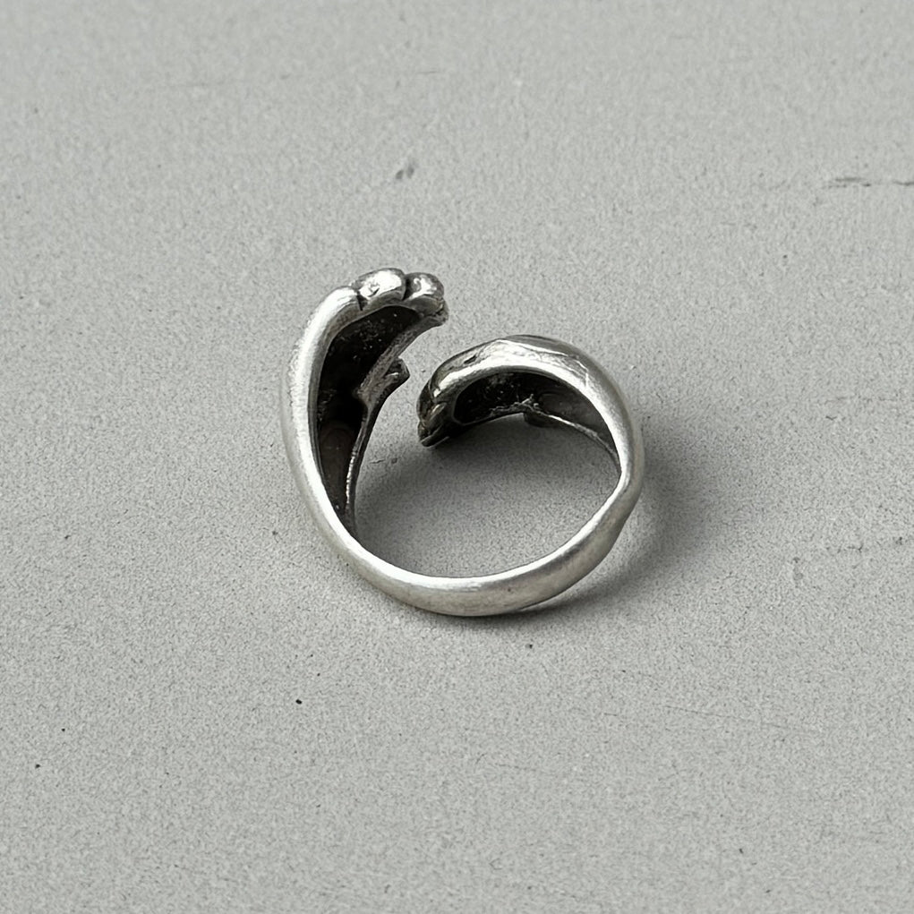 a photo of the back of a silver ring with a double hugged hands design