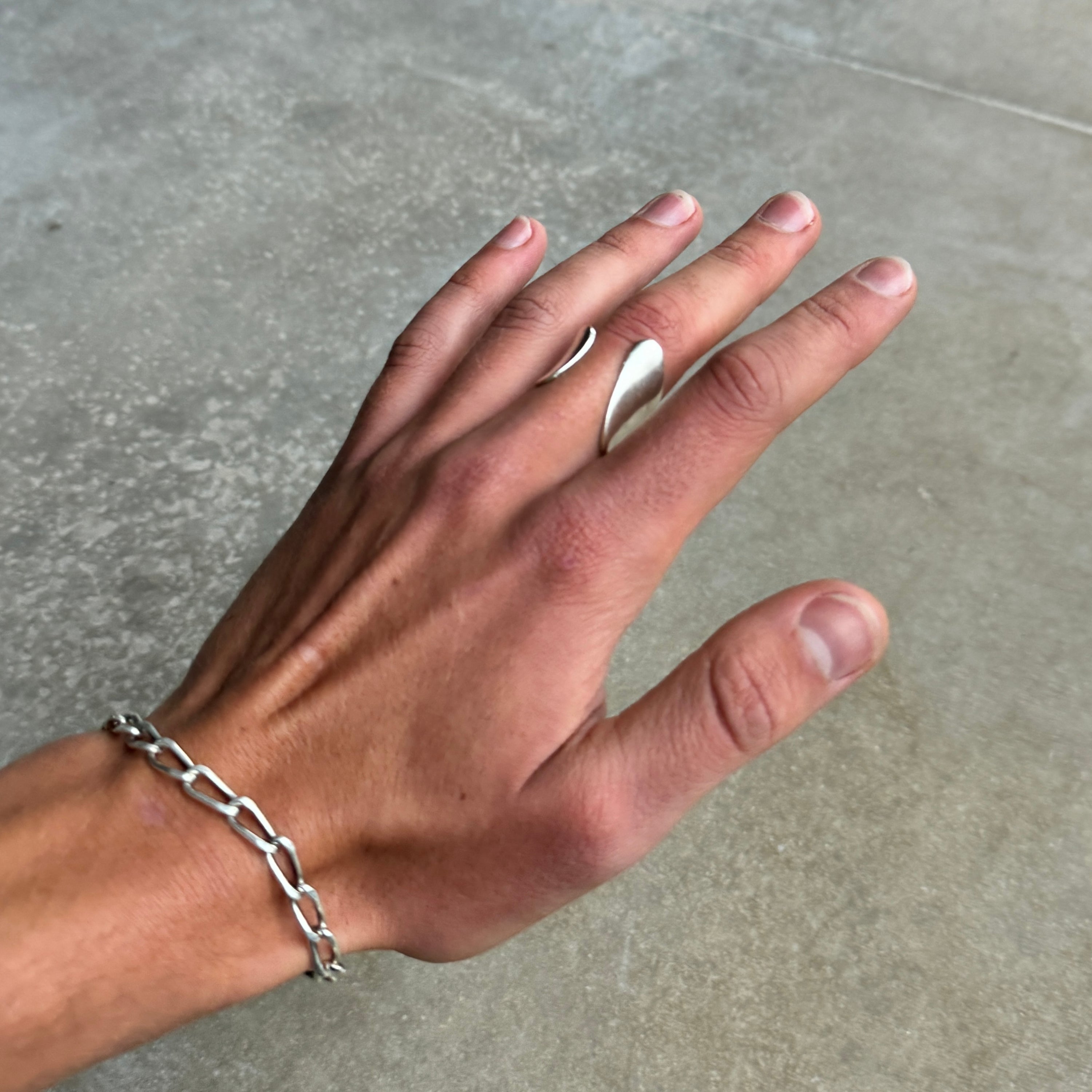 photo of a hand wearing a silver ring with an abstract asymmetric design