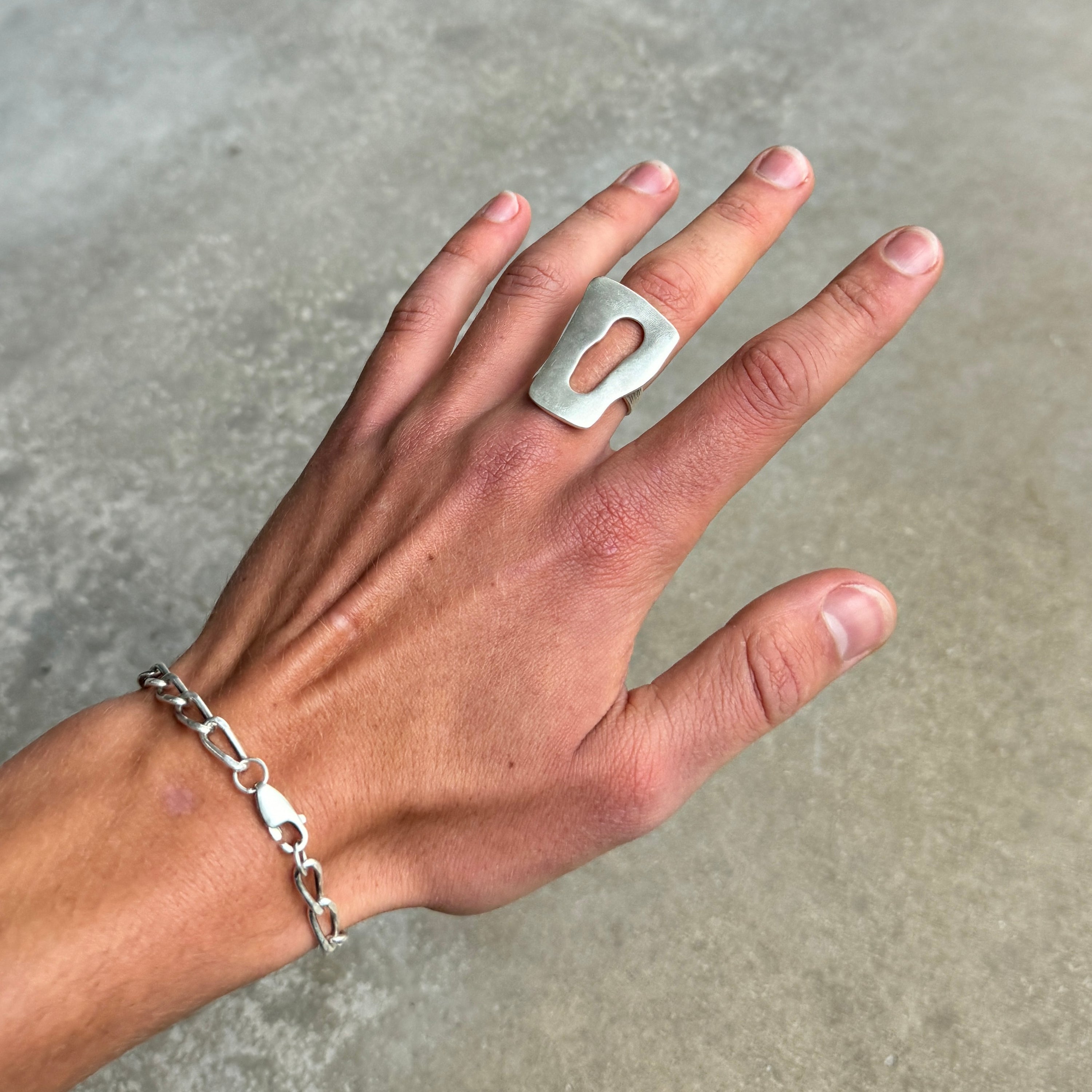  photo of a hand wearing a silver ring with an oversized abstract statement design and vintage silver finish