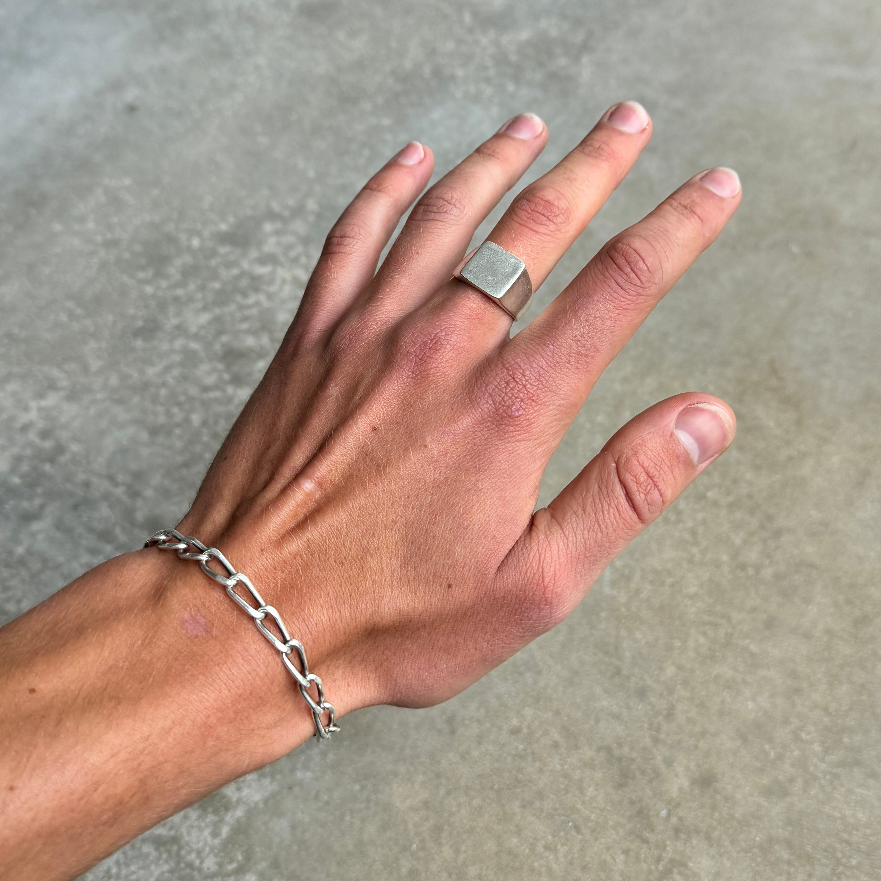 photo of a hand wearing a square silver signet ring