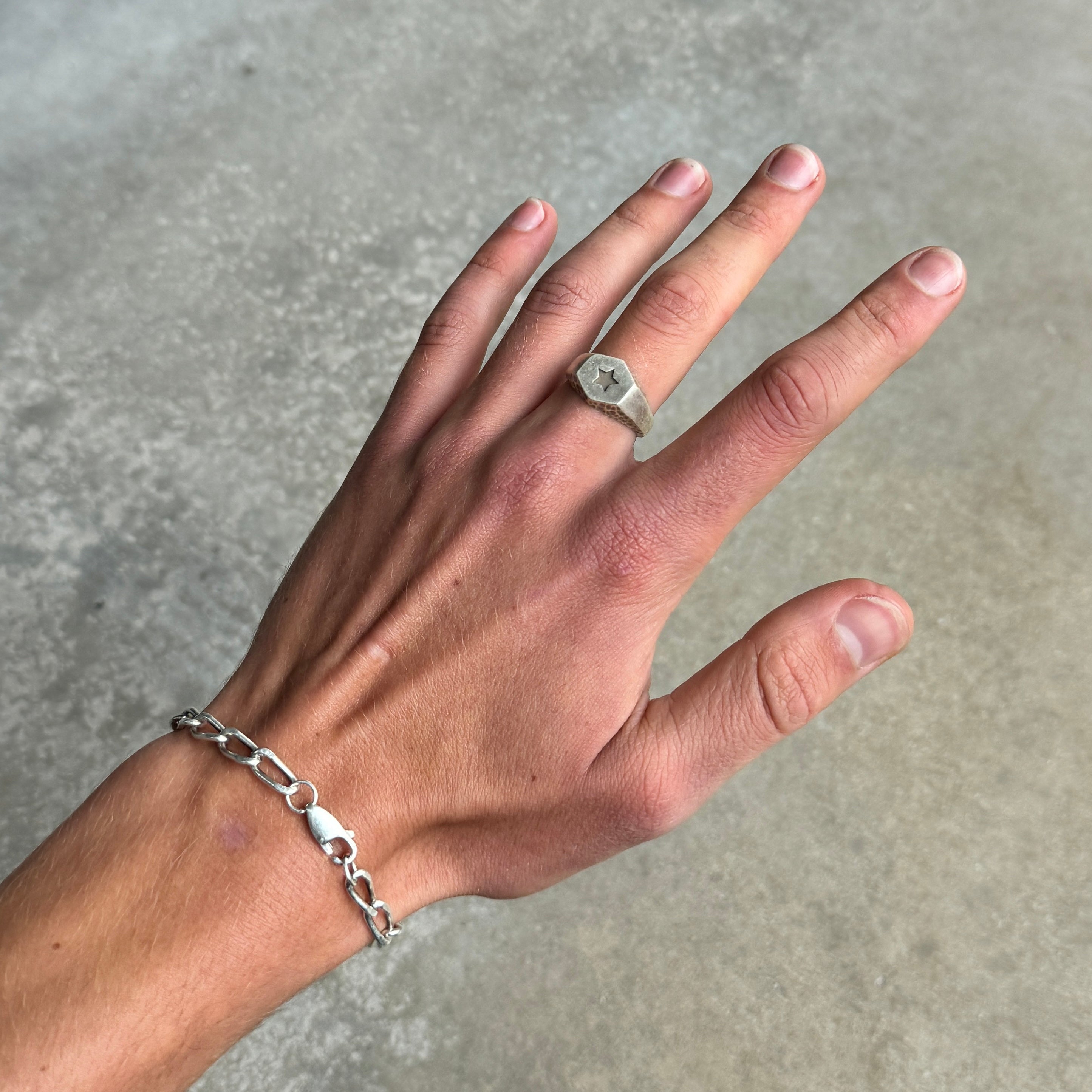 photo of a hand wearing a silver signet ring with a star design engraved on the front