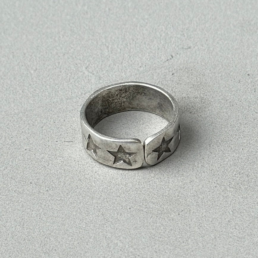 a photo of the back of a silver ring with a stamped star design and vintage silver finish