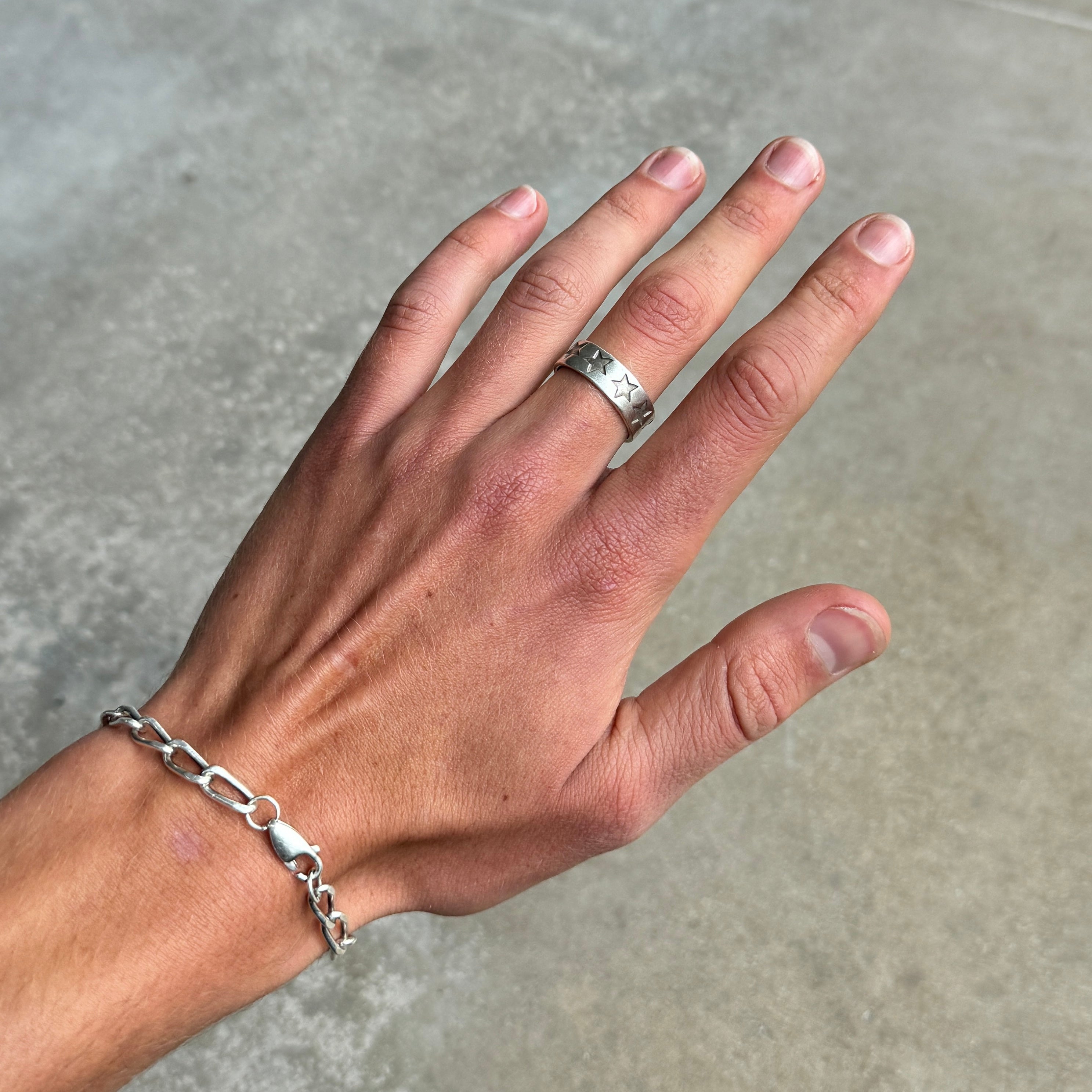 a photo of a hand wearing a silver ring with a stamped star design and vintage silver finish